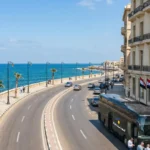 Daily Sun Travel VIP tour bus and guide with tourists outside an Alexandria boutique hotel. Premier B2B DMC ground handling in Egypt.